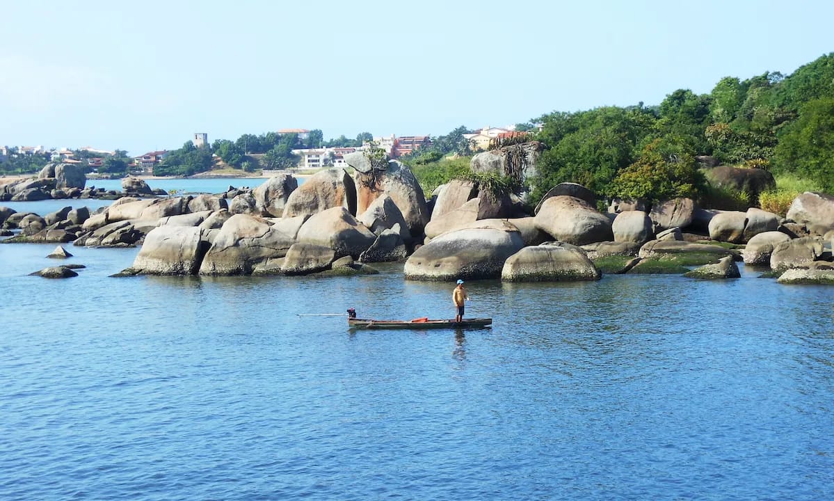 Litoral de Vitória ES com formação rochosa e mar calmo Paisagem do litoral de Vitória Espírito Santo com pedras e pescador